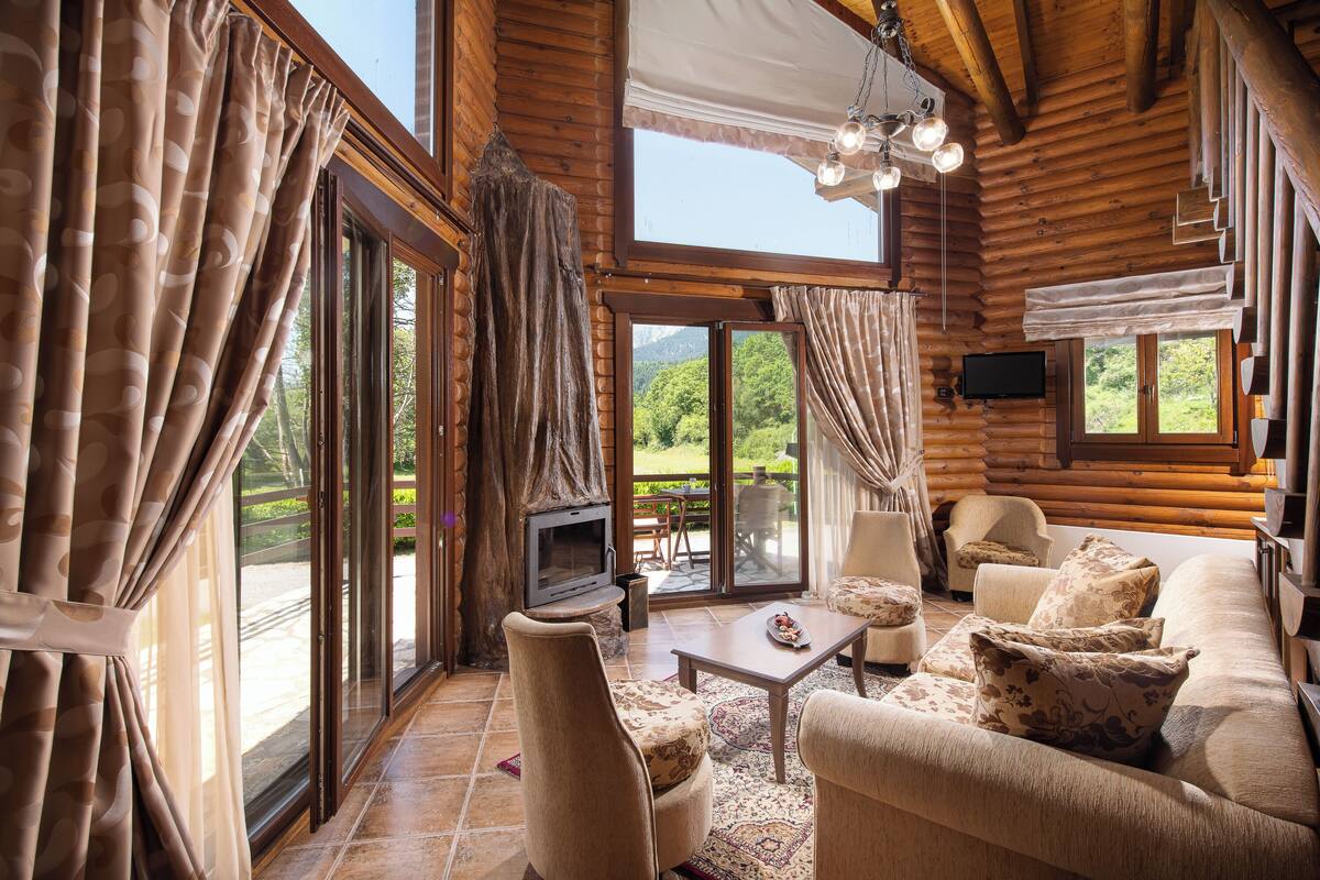 A log cabin interior with a fireplace, sofa, and television.