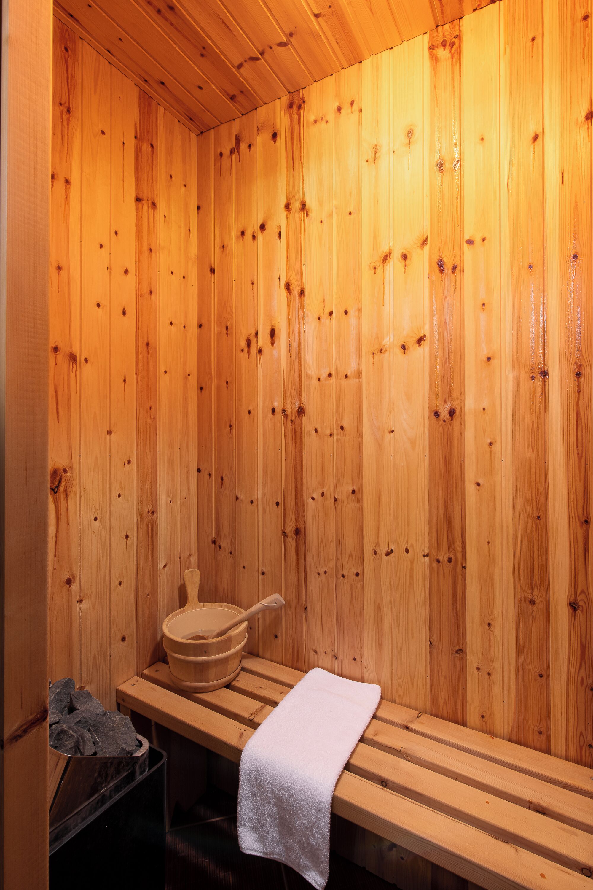 A wooden sauna with benches and a wooden bucket.