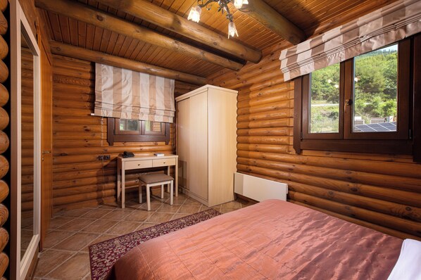 A log cabin bedroom with a bed, desk, chair, and wardrobe. - Natura Chalets (Karpenisi)