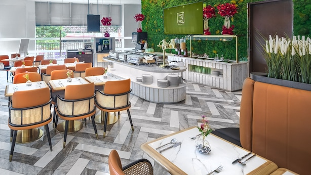 Un restaurante moderno con una pared verde, sillas naranjas y una barra con televisor.