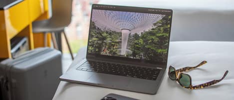 A laptop on a table with a smartphone and a pair of sunglasses beside it.