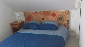 A bedroom with a bed, a nightstand, and a wall with a decorative pattern.