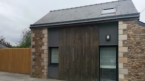 A modern building with a stone facade, a large wooden door, and two windows.