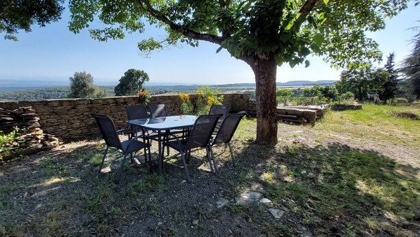 Een terras met stenen muren en een tafel met stoelen, met uitzicht op een prachtig landschap.