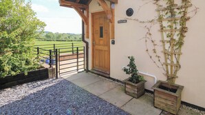 A wooden door with a small porch and a view of a green field. - Mossy Lodge (Shrewsbury)
