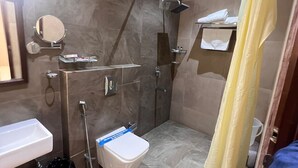 A modern bathroom with a shower, toilet, sink, and a mirror.