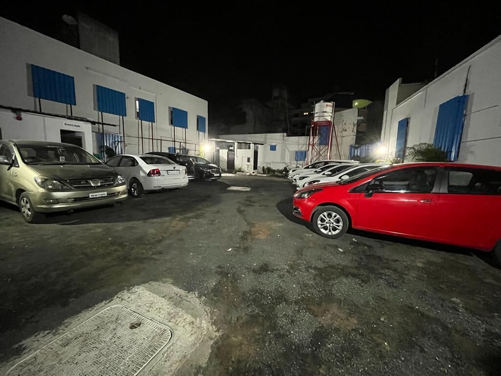 A parking area with several cars, a water tower, and buildings with blue shutters.