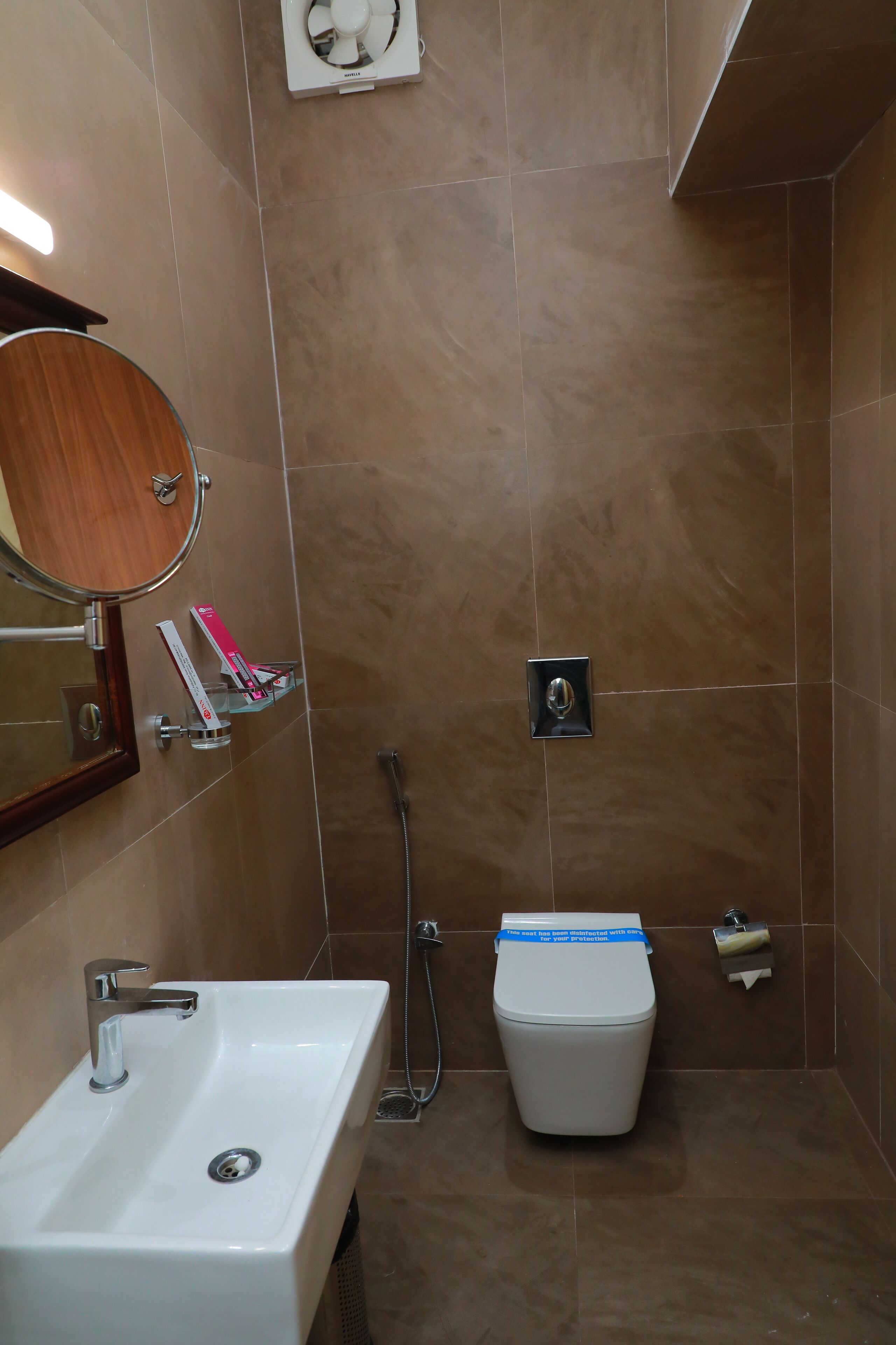 Ein Badezimmer mit Waschbecken, Spiegel, Toilette und Handtuchspender.