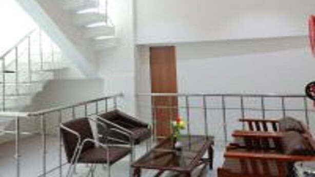 A modern interior with a staircase, seating area, and a view of the outdoors. - TM Inn (Kanchipuram)