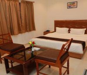 A hotel room with a wooden bed, a wooden table, and a chair.