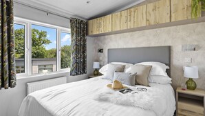 Camera da letto con un letto grande, testiera in legno e vista sull'esterno attraverso una finestra.