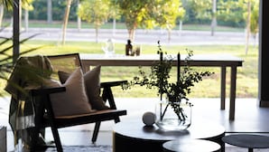 A modern living room with a sofa, coffee table, and a view of a garden. - The Woods Luxury Homes - Elaleni Estate (Ballito)