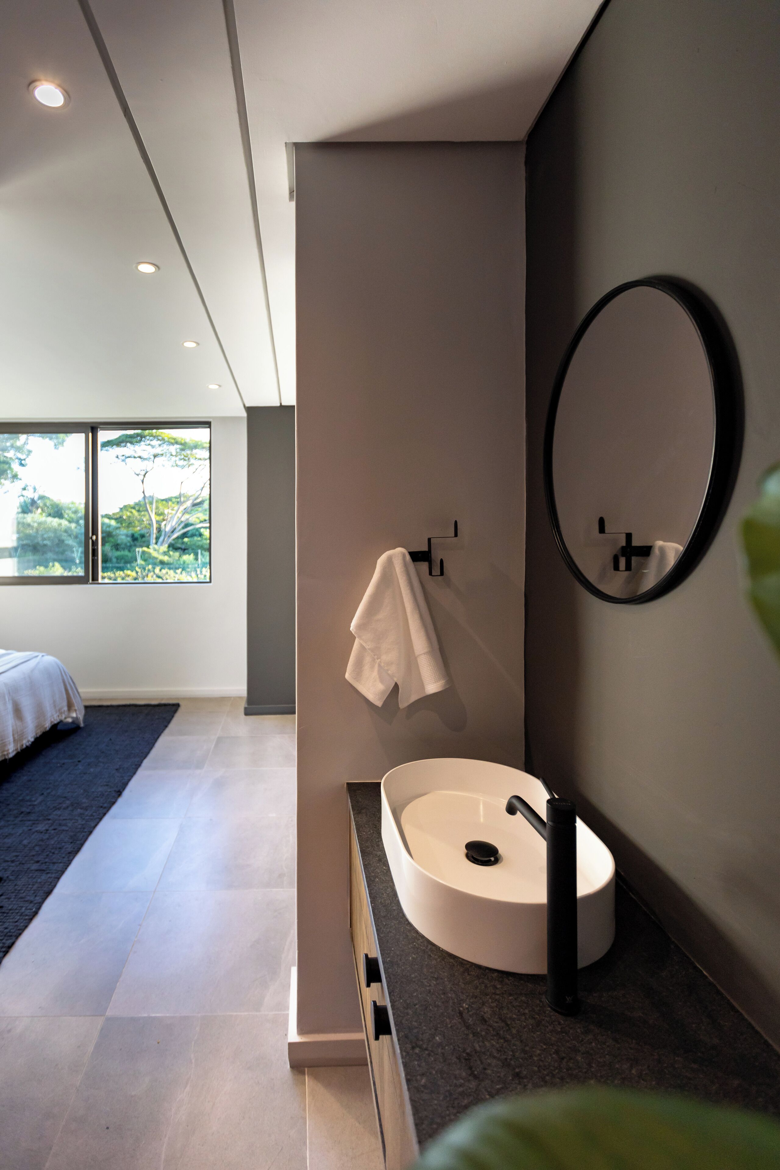 Une salle de bain moderne avec un lavabo rond, un miroir et une serviette suspendue à un porte-serviettes.