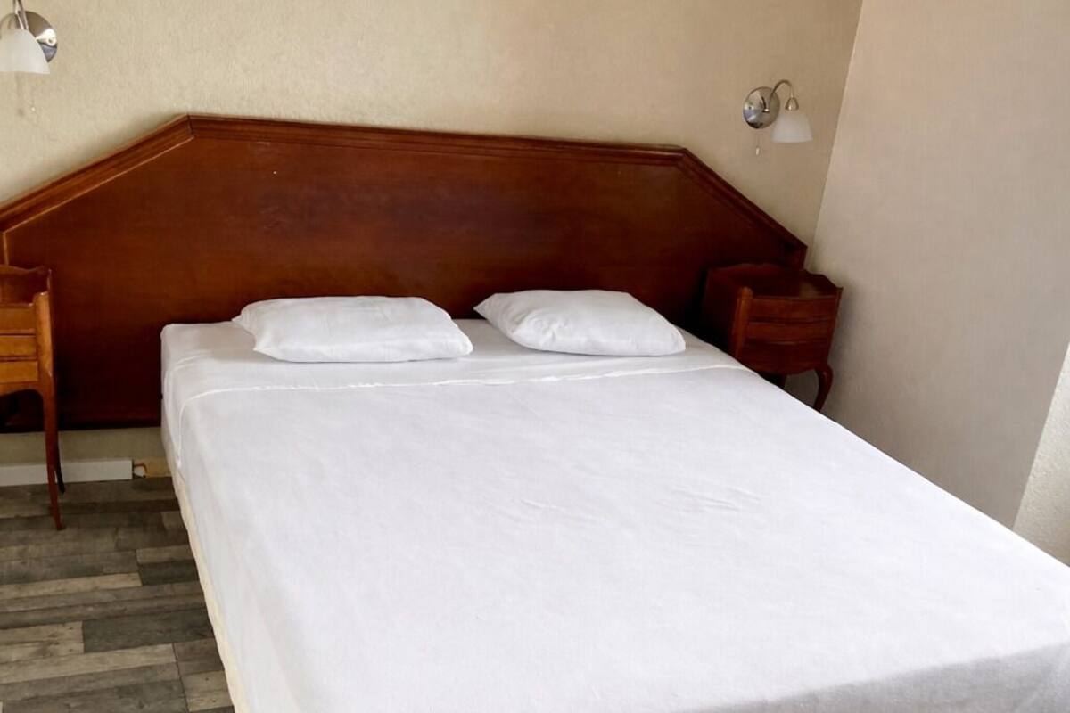 A bed with a wooden headboard, two pillows, and a white bedspread.