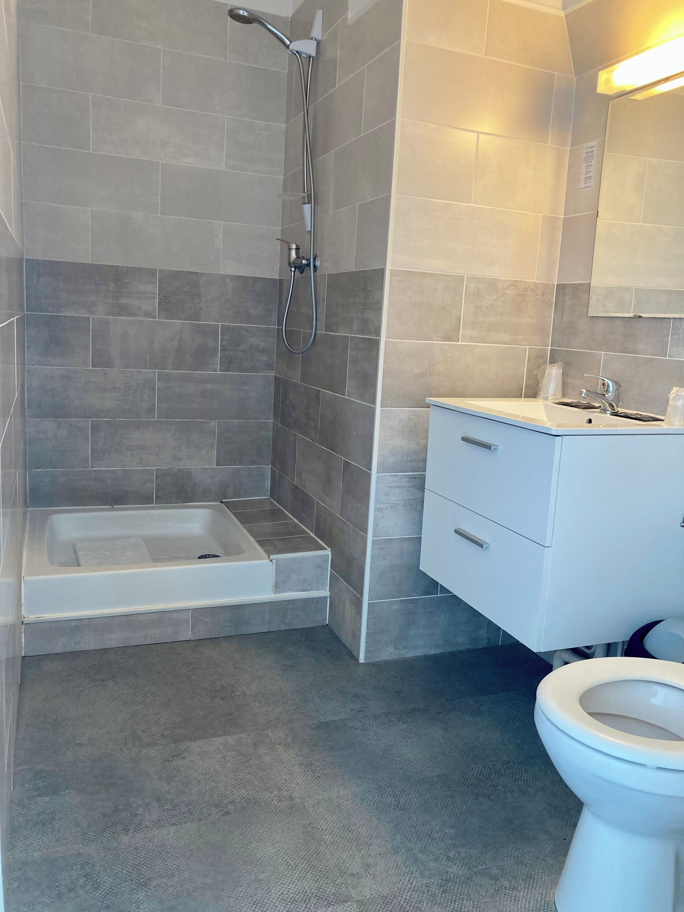 Un baño moderno con ducha, bañera, inodoro y tocador con espejo.