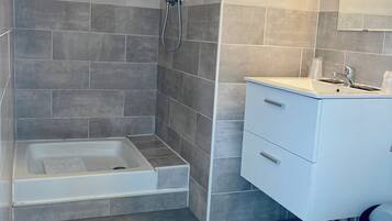 Un baño moderno con ducha, bañera, inodoro y tocador con espejo.