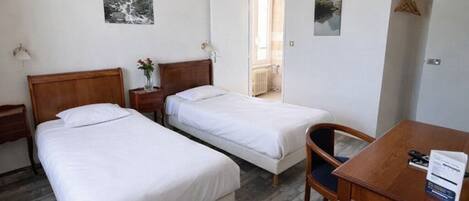 Una habitación de hotel con dos camas, un escritorio de madera, una silla y una mesita.