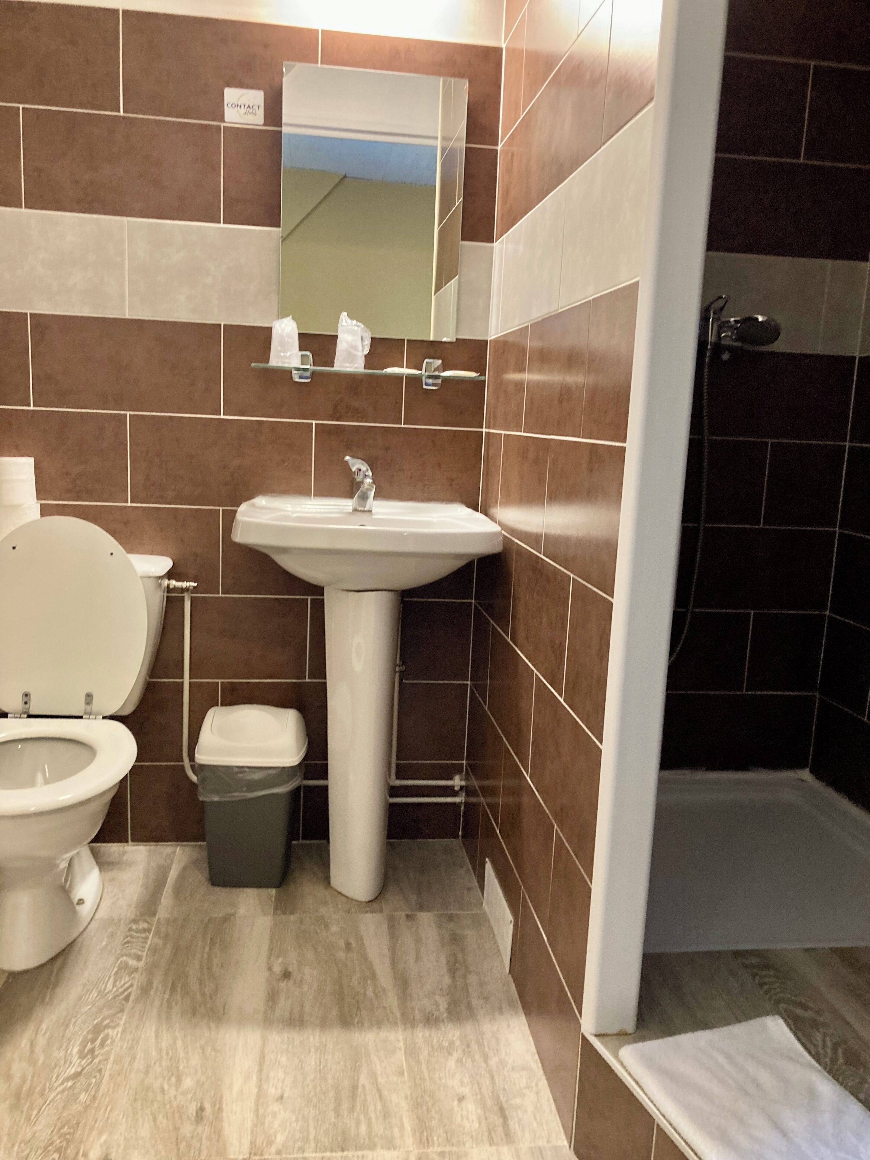 Een badkamer met toilet, wastafel en douche.