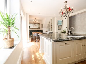 A modern kitchen with a large island, white cabinetry, and a chandelier.