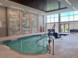 Una piscina interior con agua cristalina, suelo de baldosas y pared de piedra.