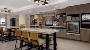 Een moderne eethoek met een centraal kookeiland, zitplaatsen en een keuken op de achtergrond.