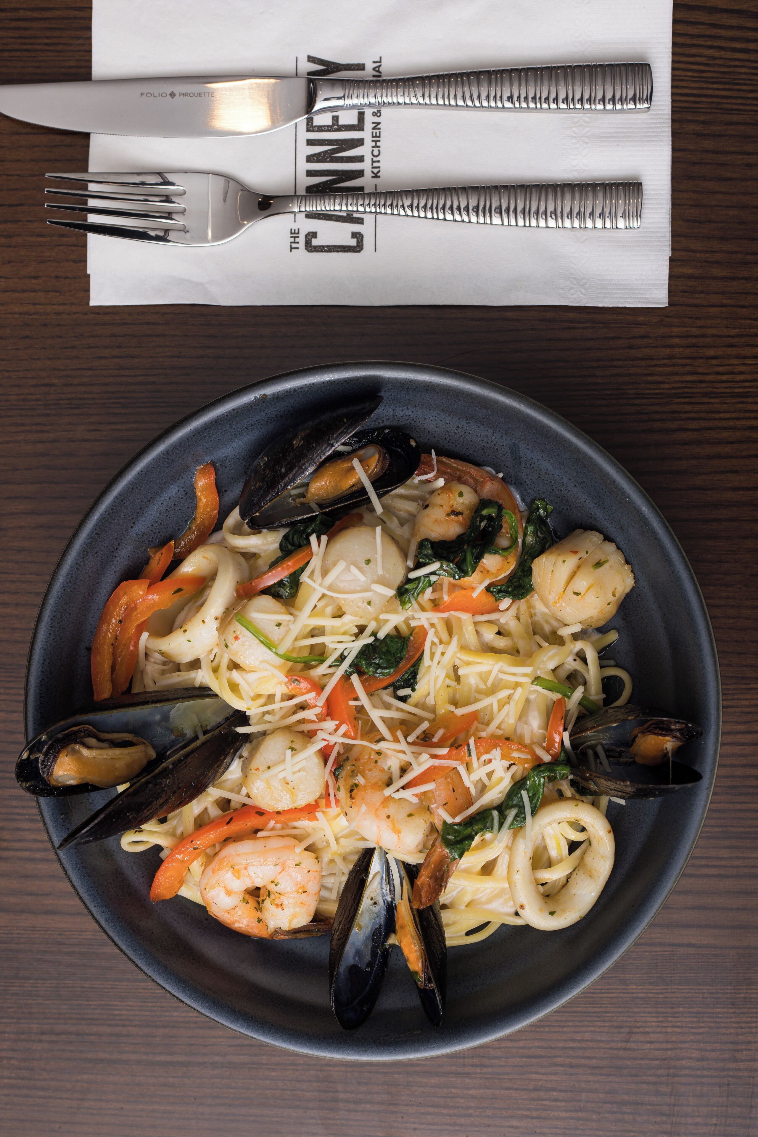 Une assiette de pâtes aux crevettes, aux moules et aux légumes.
