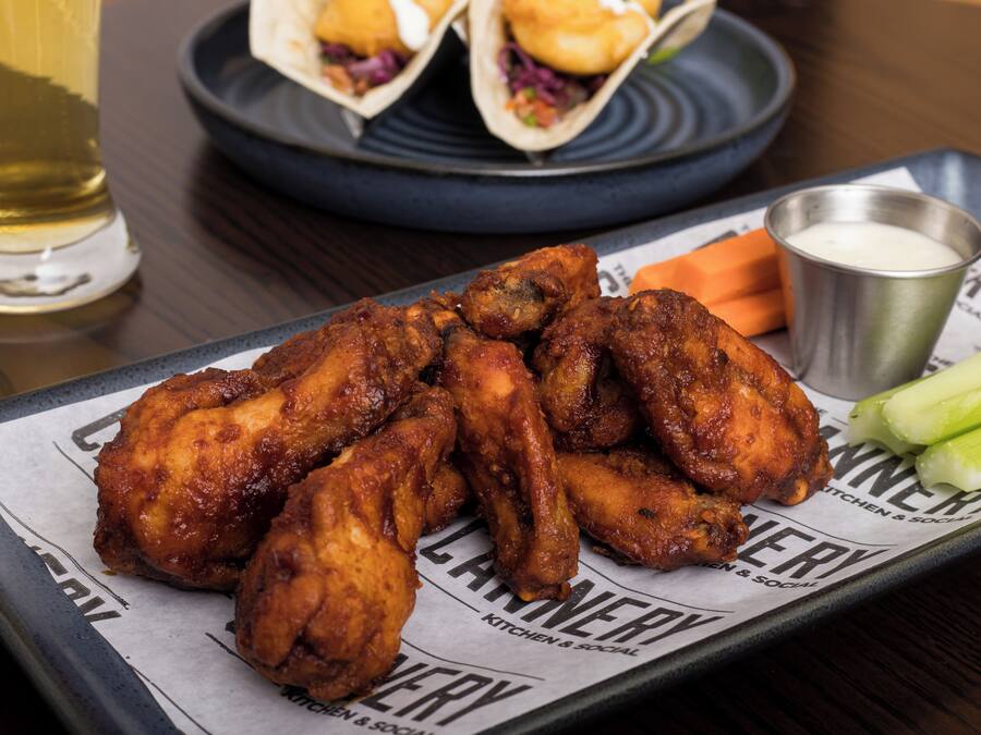 Un plateau contenant des ailes de poulet frites, des bâtonnets de céleri et une sauce pour tremper.