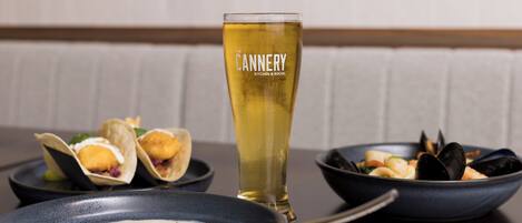 A dining table with seafood dishes, a bowl of soup, and a tall glass of beer.