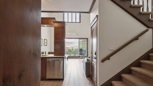 A modern kitchen with a dishwasher, a wooden cabinet, and a view through a glass door to an outdoor balcony. - Tremblant Prestige - Manoir 120-6 (Mont-Tremblant)