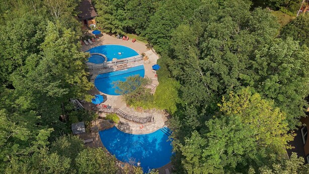 An aerial view of a resort with two swimming pools surrounded by lush greenery. - Tremblant Prestige - Manoir 120-6 (Mont-Tremblant)