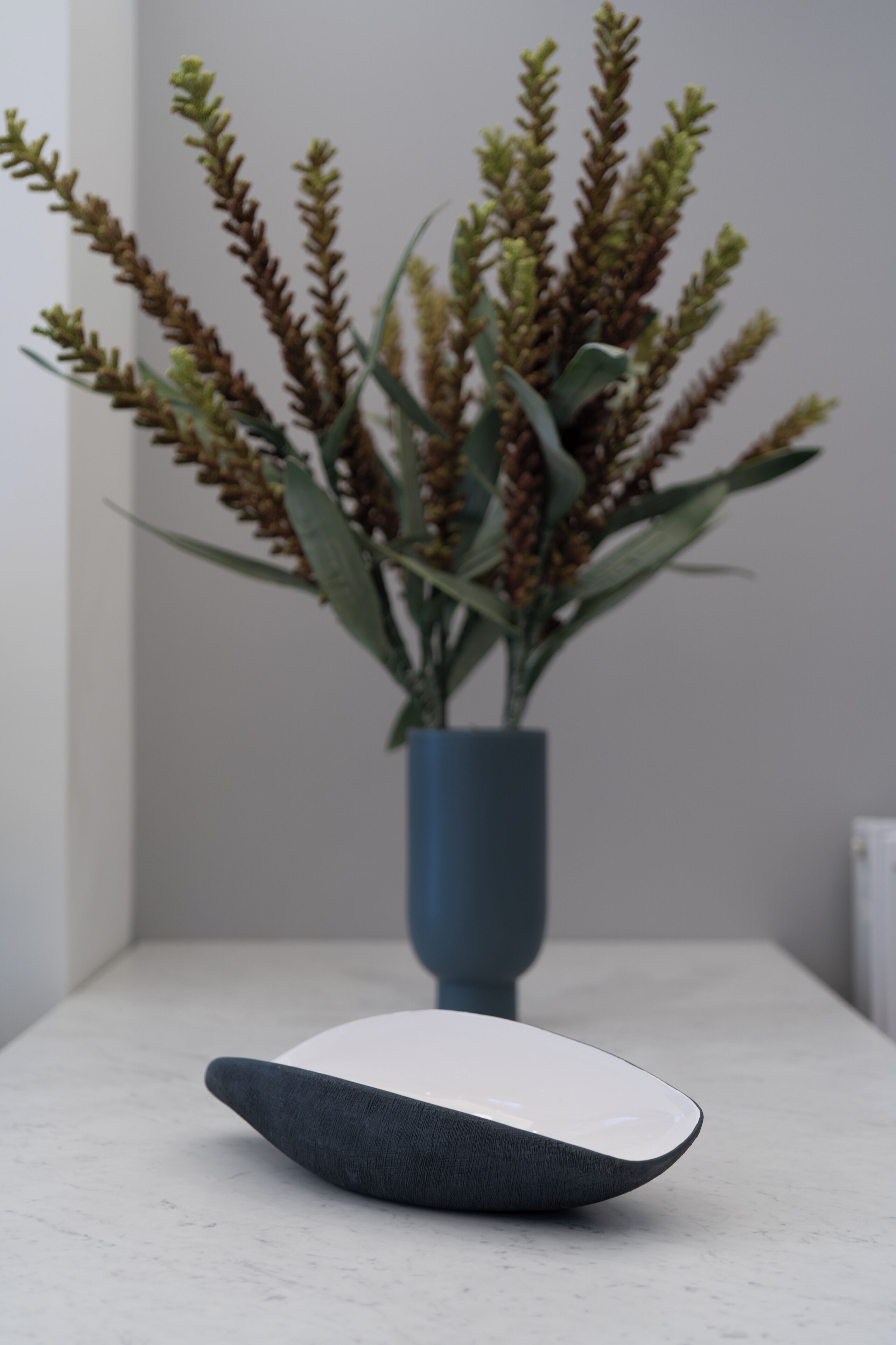 A modern table with a vase of green plants.