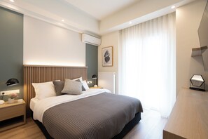 Een moderne slaapkamer met een groot bed, nachtkastjes, een airconditioner, een ingelijst kunstwerk aan de muur en een raam met gordijnen.