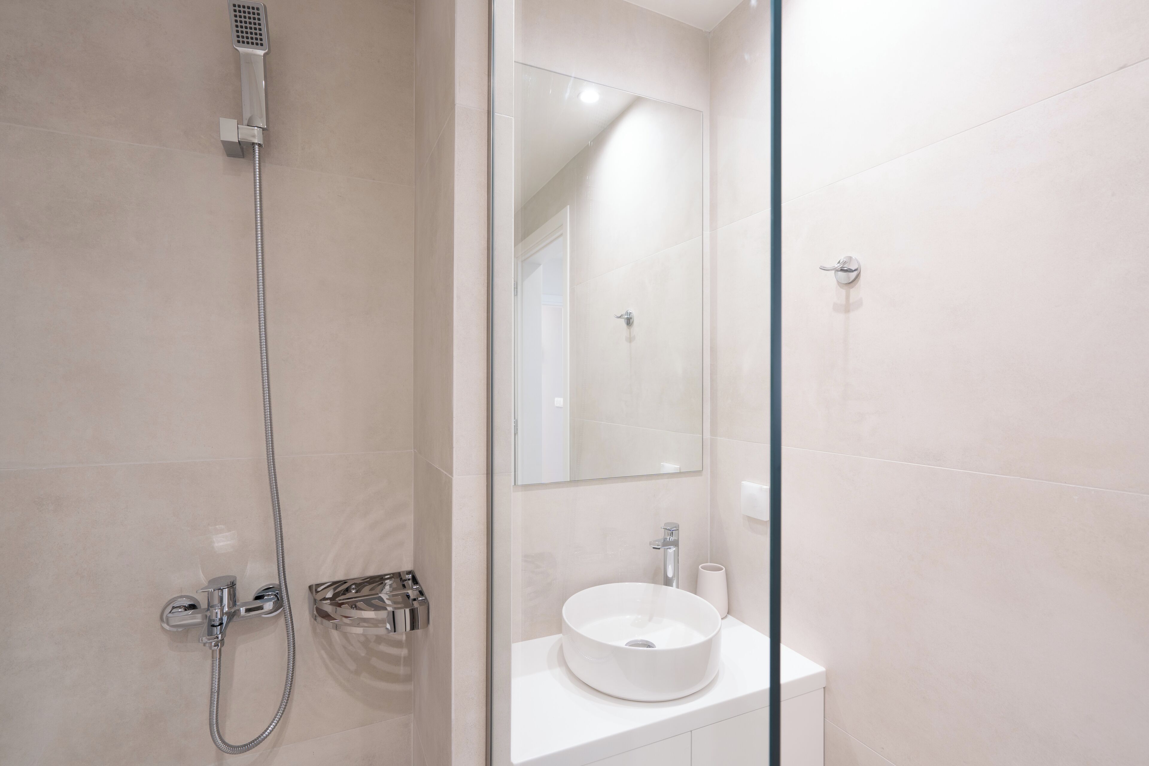 Une salle de bain moderne avec une douche à parois de verre, un lavabo blanc et un miroir.