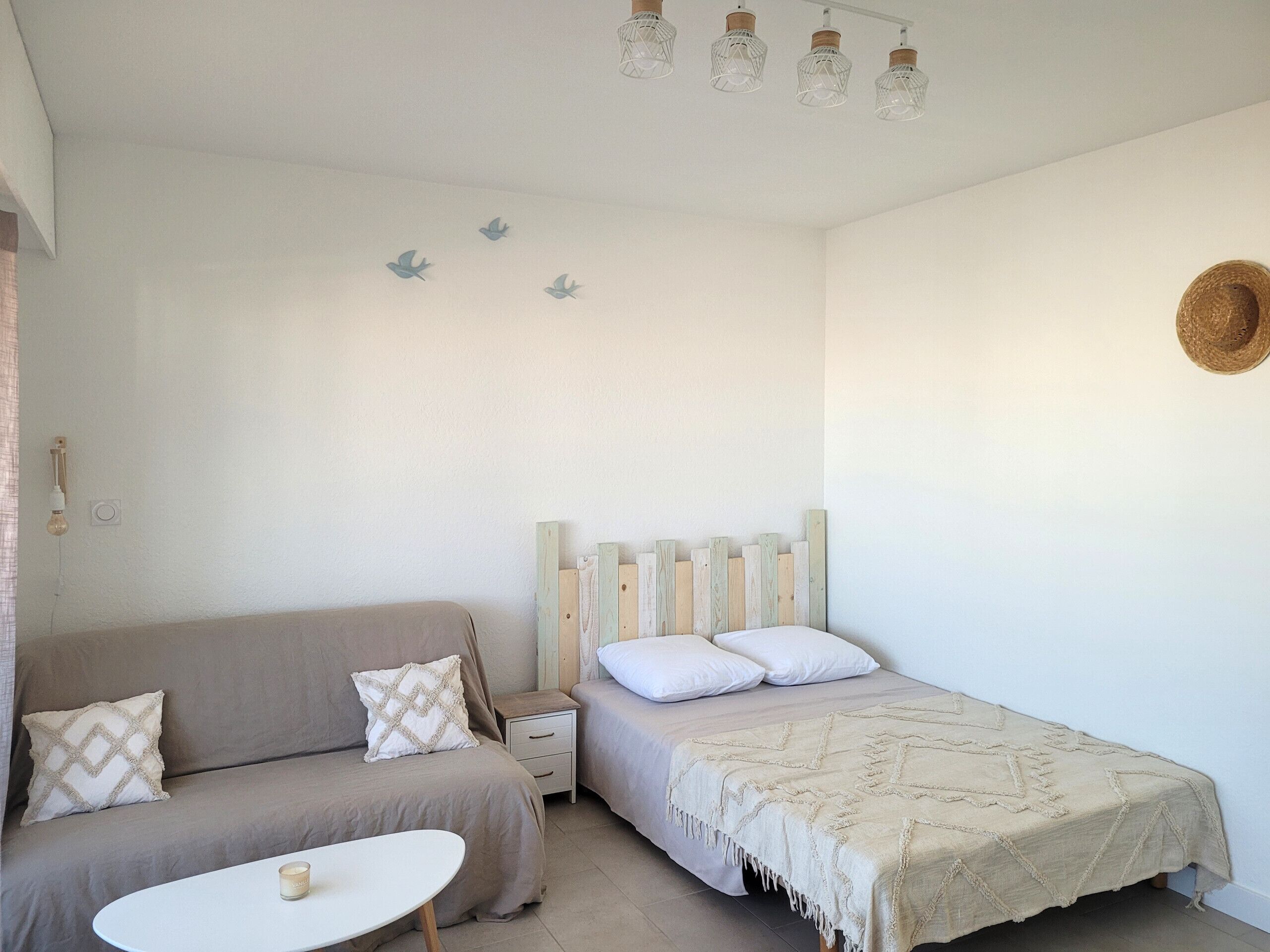 A bedroom with a bed, a nightstand, a sofa, and a small table.