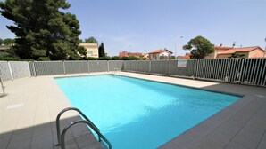 A rectangular swimming pool with a metal ladder, surrounded by a white fence, and a tiled deck. - Studio for 4 with swimming pool and parking (Canet-en-Roussillon)