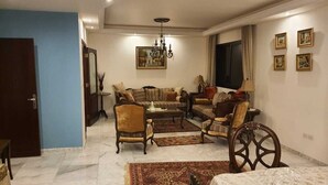 A spacious living room with a sofa set, armchairs, a coffee table, and a chandelier.