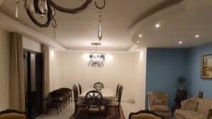 A dining area with a chandelier, a dining table with chairs, and a blue accent wall.