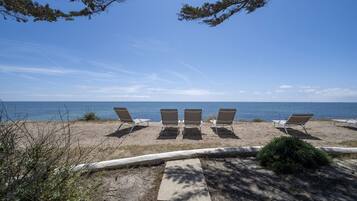 Relax on six sun loungers aligned along the shoreline, offering a clear view of the calm sea.