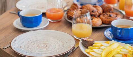 A breakfast table with plates, cups, and a glass of orange juice.