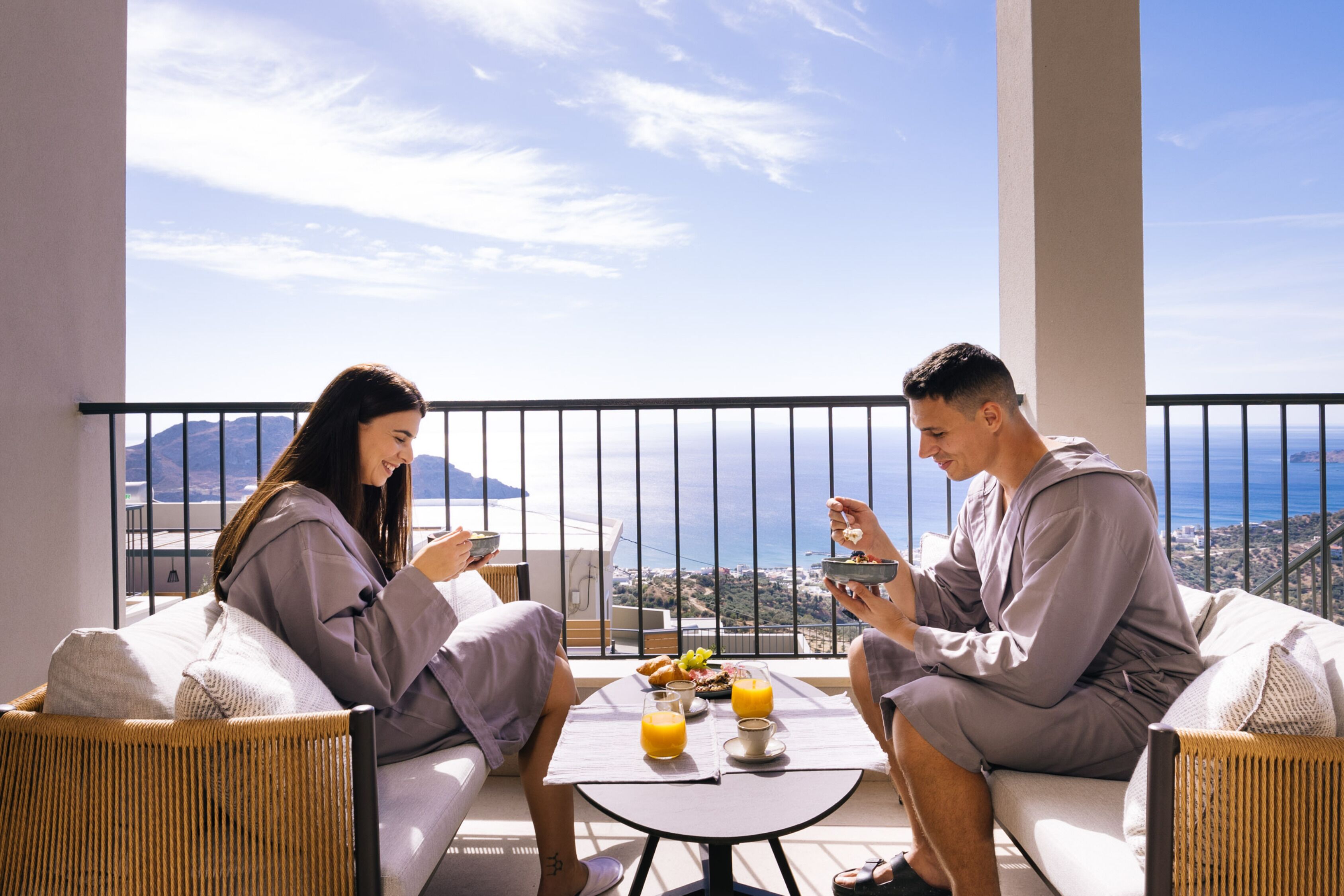 A balcony with a table set for breakfast, overlooking a scenic view.