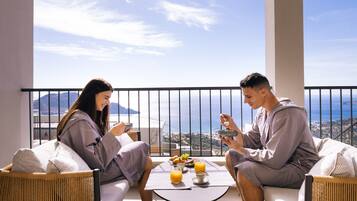 A balcony with a table set for breakfast, overlooking a scenic view.