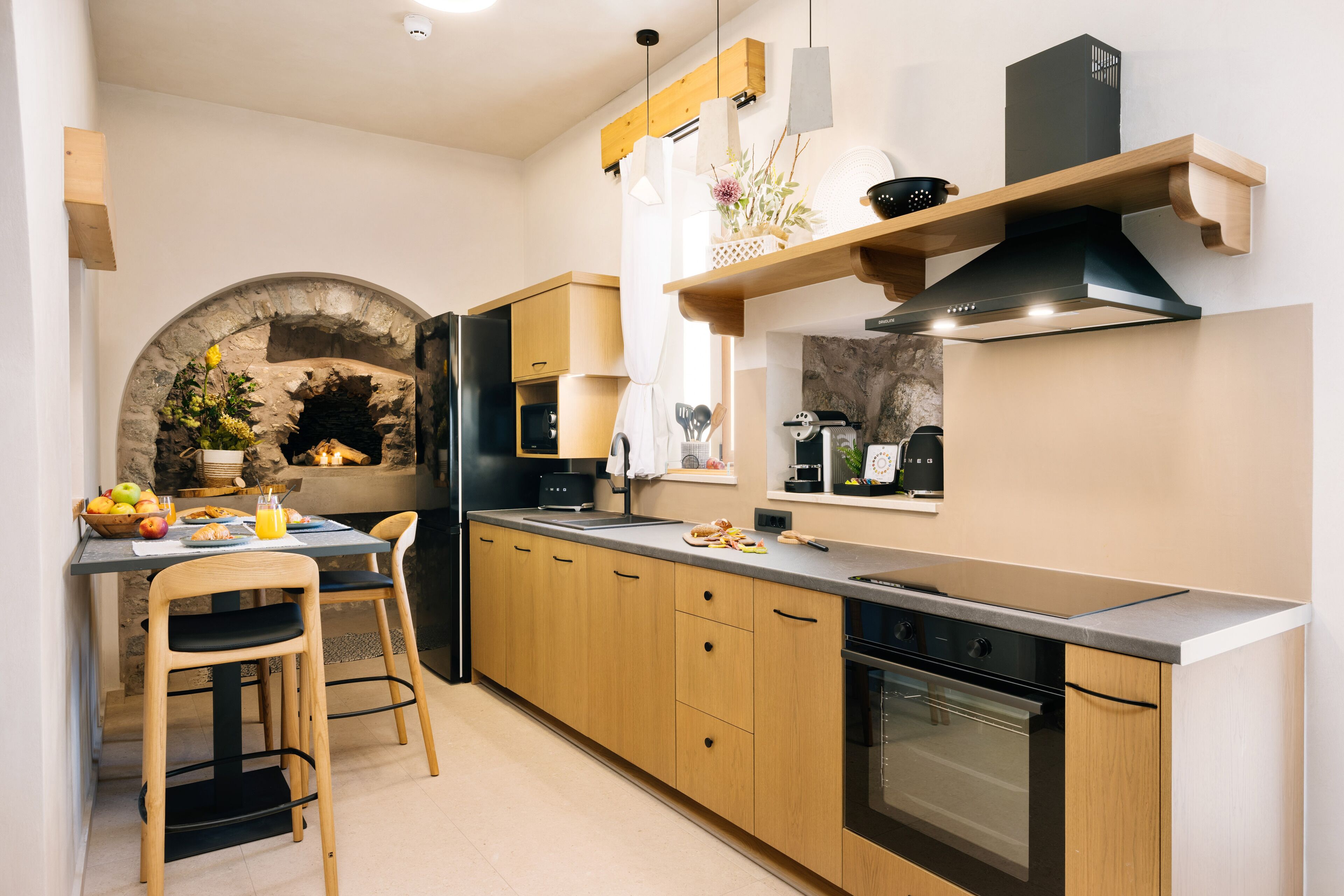 A modern kitchen with wooden cabinets, a built-in oven, and a stone archway.