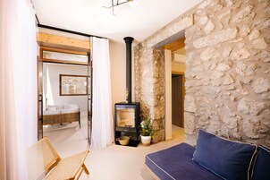Une pièce chaleureuse avec un mur en pierre, un canapé, un fauteuil en osier et une cheminée.