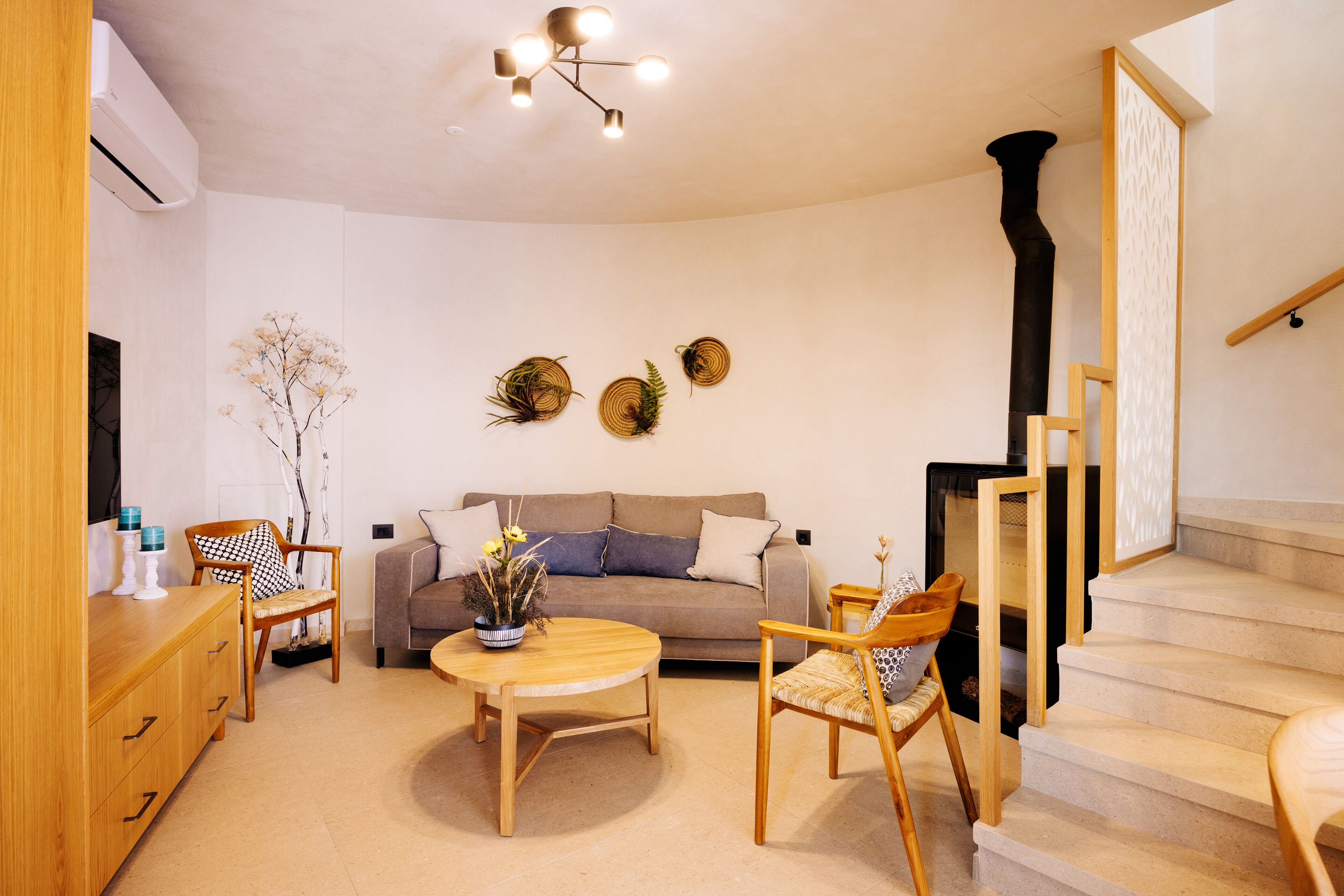 En moderne stue med sofa, to stole, et sofabord og en trappe.
