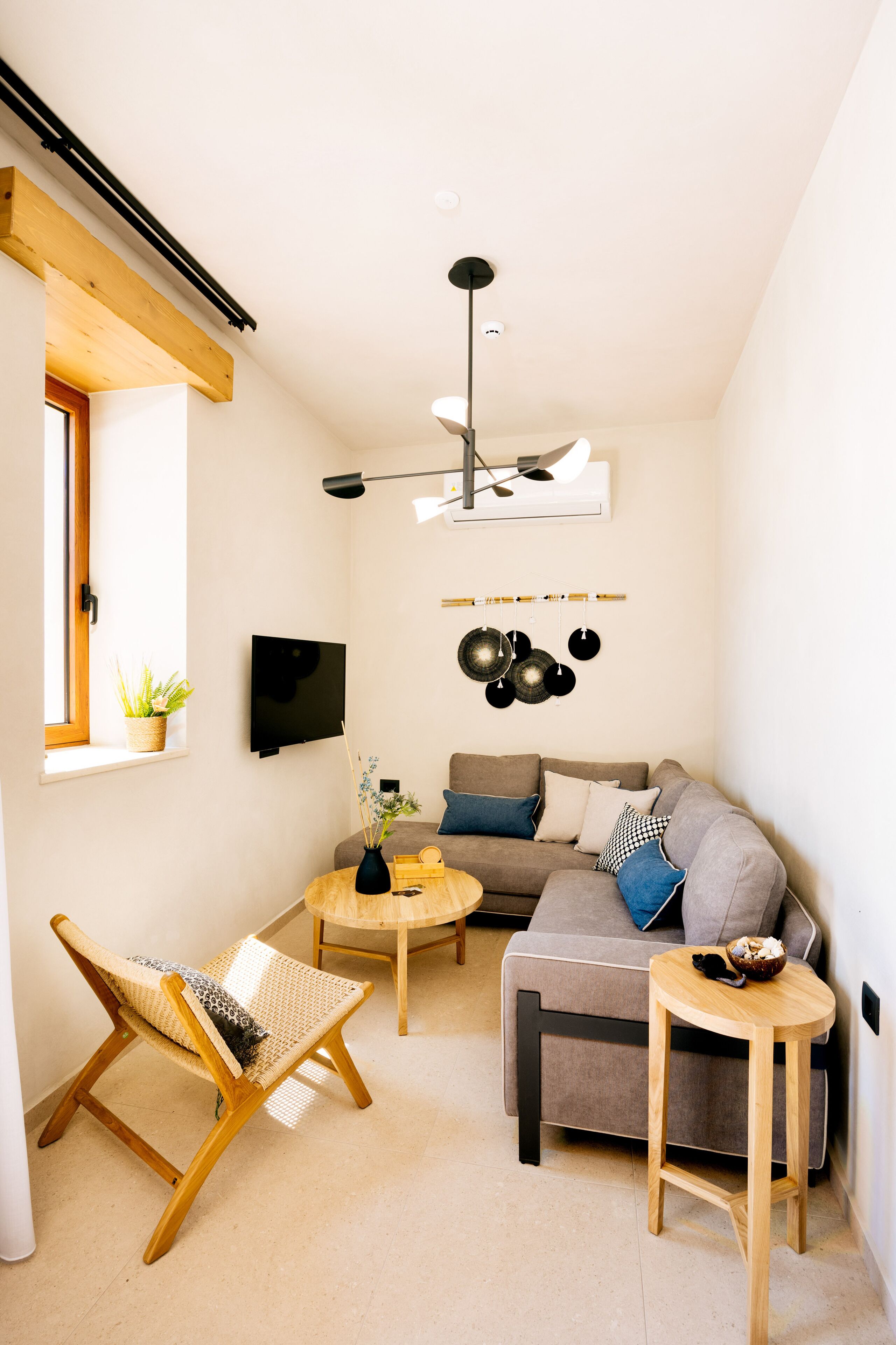 A modern living room with a sofa, a chair, a coffee table, and a hanging pot rack.