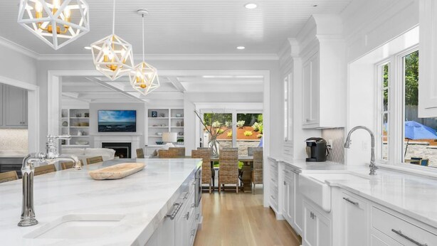 A modern kitchen with white cabinetry, a large island, and pendant lighting.