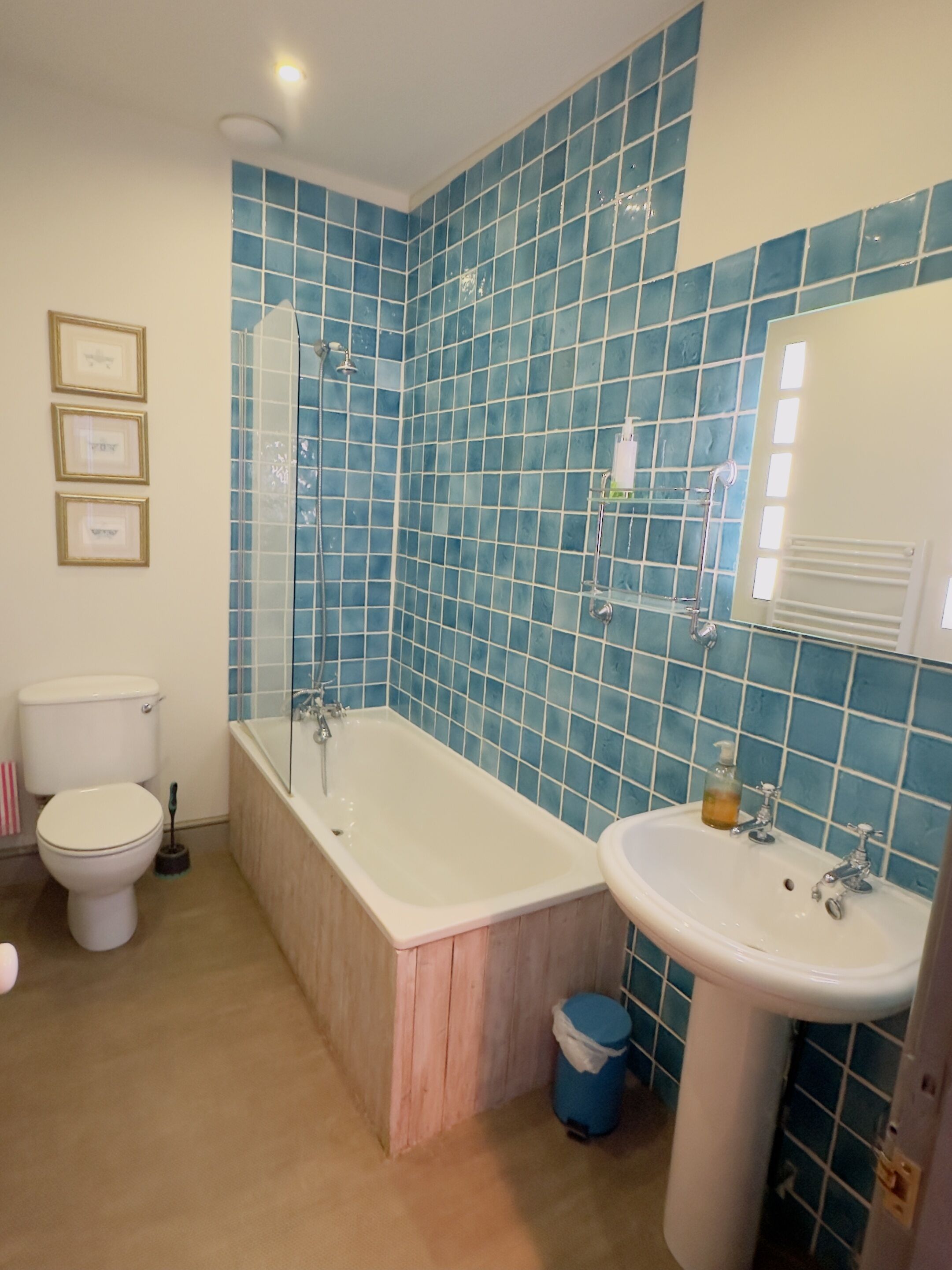 A bathroom with a bathtub, sink, toilet, and blue tiled walls.