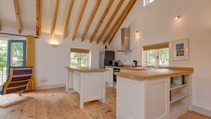 A spacious kitchen with wooden beams, white cabinetry, and a large island. - Owl Barn -  a self catering cottage that sleeps 6 guests  in 3 bedrooms (Morston)