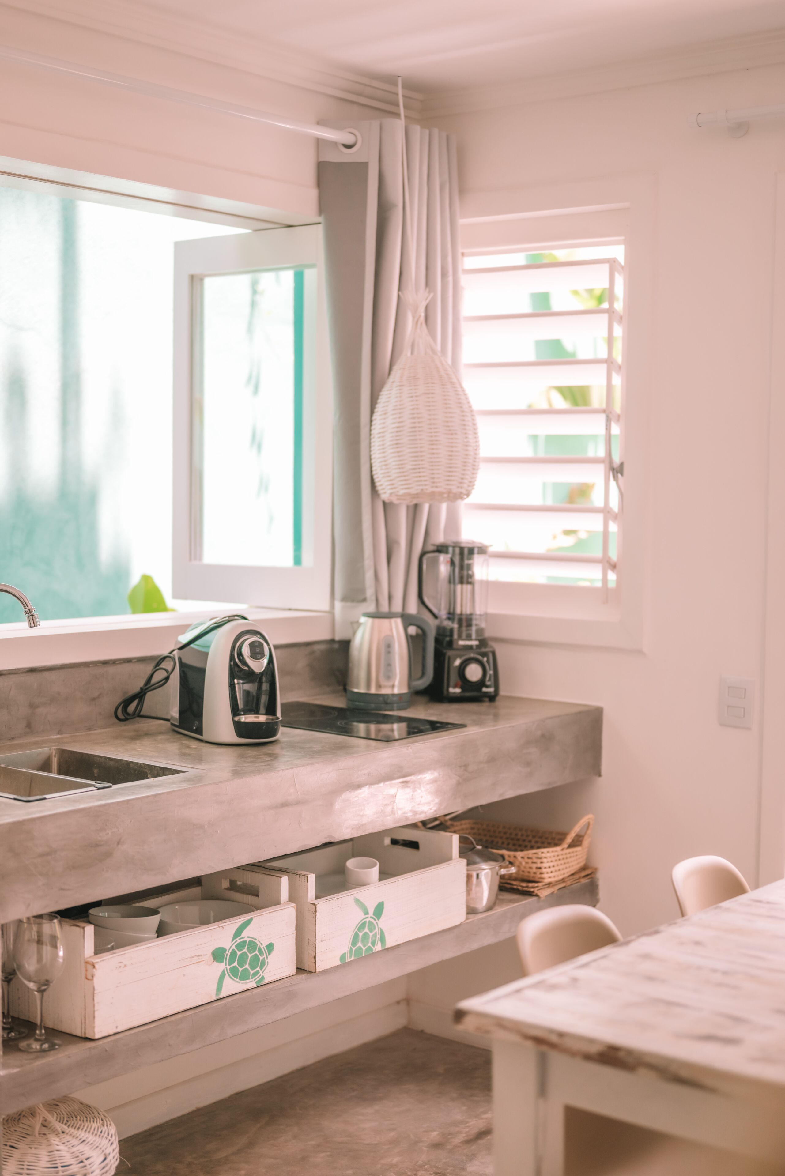 Una cocina con ventana, hervidor, cafetera y tostadora.