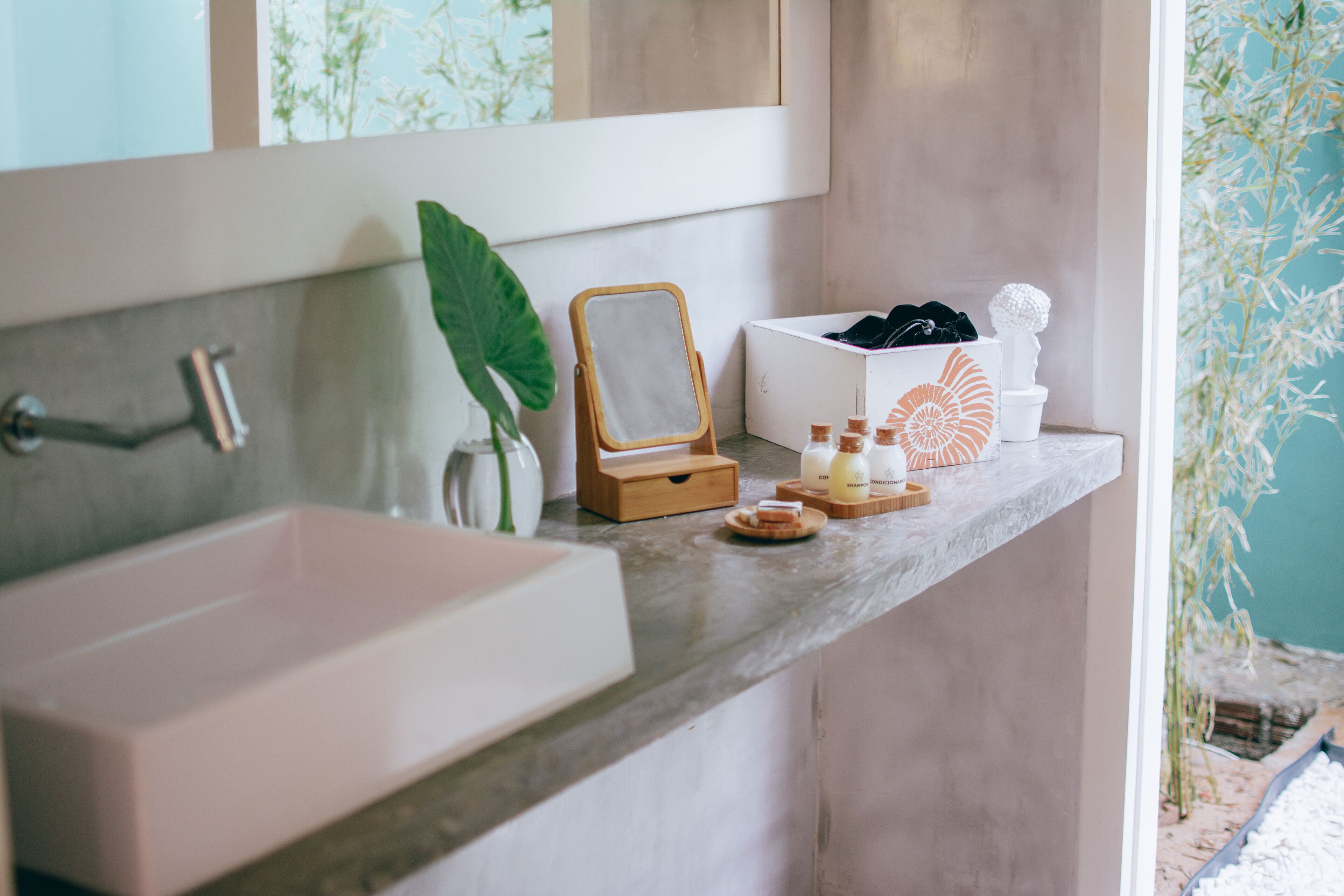 Casa de banho com uma pia grande, um espelho e uma prateleira com produtos de higiene e objetos decorativos.